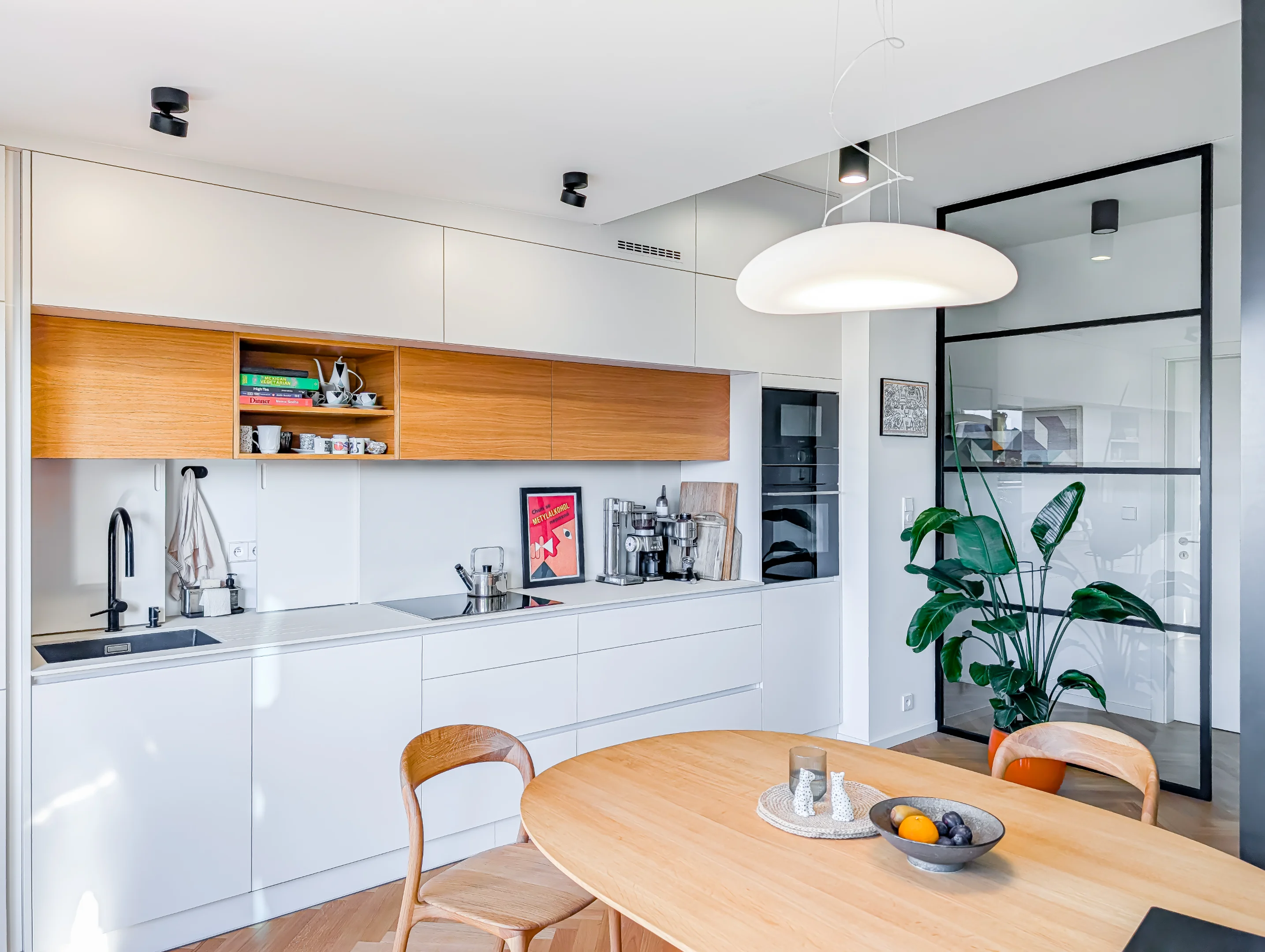 Moderní kuchyně s bílou linkou dřevěným stolem a designovým osvětlením